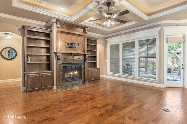 unfurnished living room with a high end fireplace, ornamental molding, coffered ceiling, ceiling fan, and hardwood / wood-style flooring