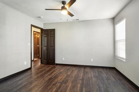 unfurnished room with ceiling fan, dark wood-type flooring, and a healthy amount of sunlight