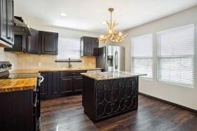 kitchen featuring pendant lighting, a center island, stainless steel refrigerator with ice dispenser, an inviting chandelier, and electric stove