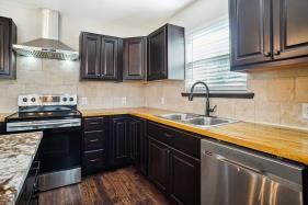 kitchen featuring wall chimney range hood, sink, appliances with stainless steel finishes, butcher block counters, and backsplash