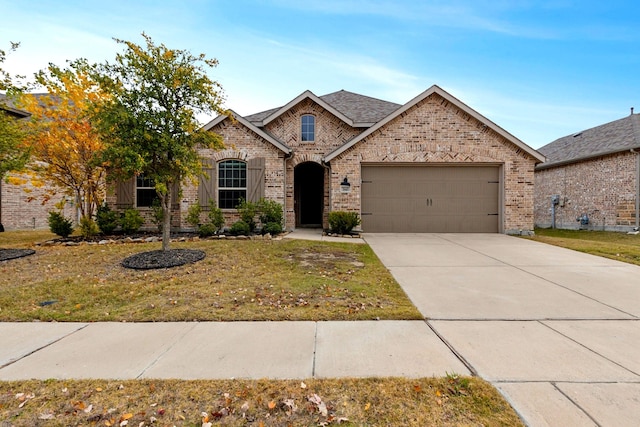 french country style house featuring a front lawn, an attached garage, brick siding, and driveway