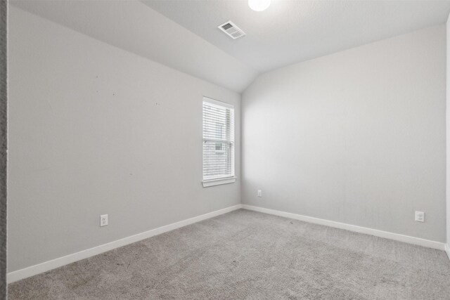 spare room with visible vents, baseboards, carpet, and vaulted ceiling