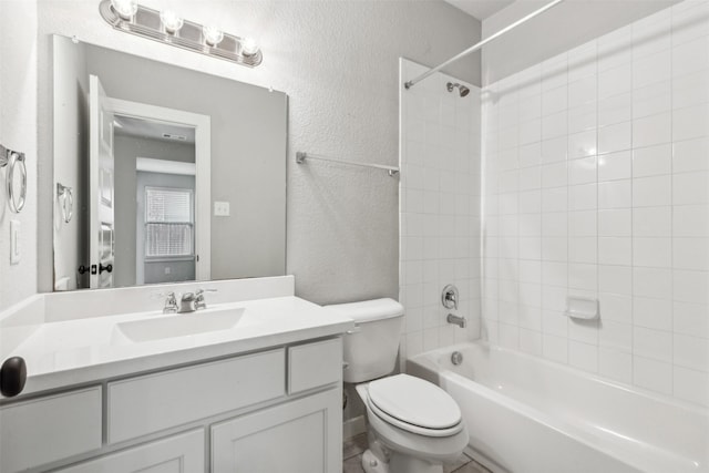 full bathroom with vanity, toilet, shower / tub combination, and a textured wall