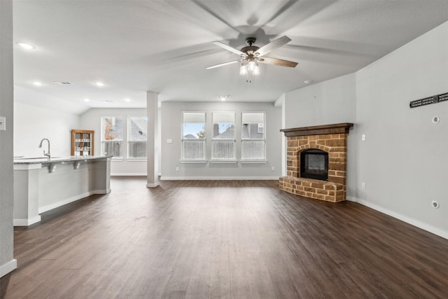 unfurnished living room with dark wood-style floors, visible vents, baseboards, ceiling fan, and a stone fireplace