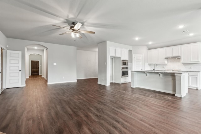 kitchen featuring white cabinets, dark wood-style floors, arched walkways, and stainless steel appliances