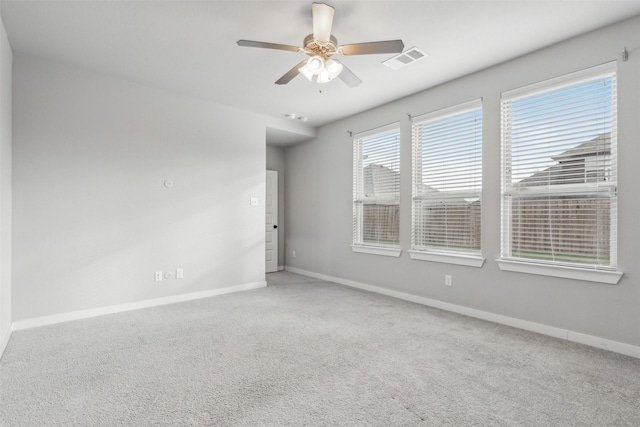 carpeted spare room with visible vents, ceiling fan, and baseboards
