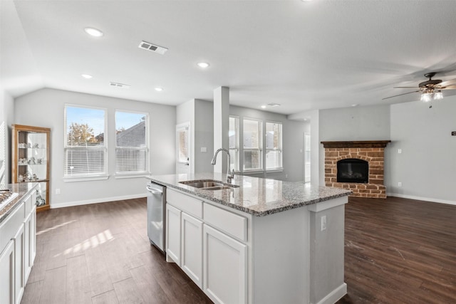 kitchen with sink, light stone counters, dishwasher, a kitchen island with sink, and white cabinets