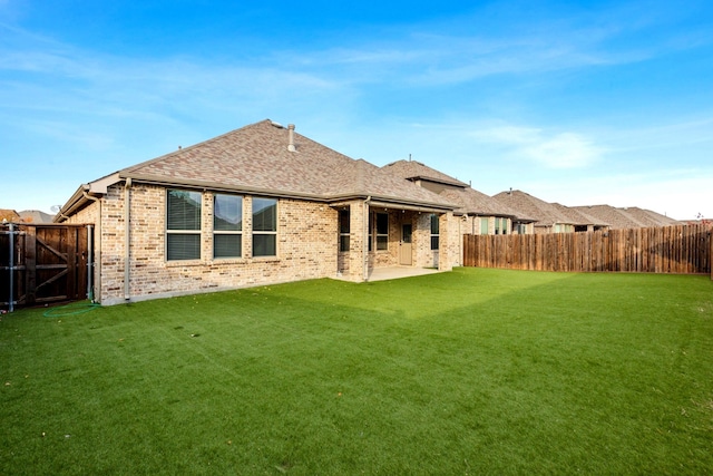 rear view of house featuring a yard, a fenced backyard, brick siding, and a shingled roof