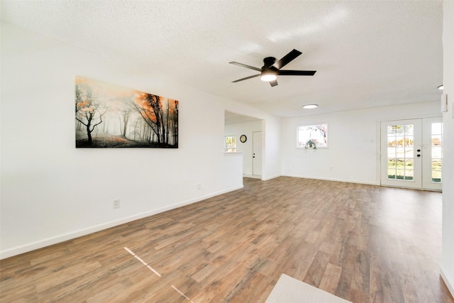 unfurnished living room with ceiling fan, wood-type flooring, french doors, and a textured ceiling