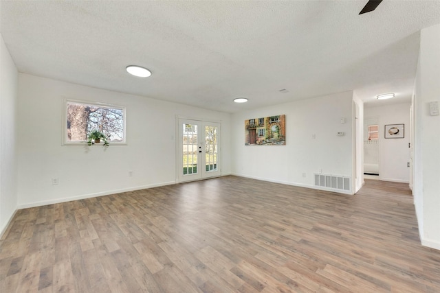 spare room with wood-type flooring, a textured ceiling, and french doors