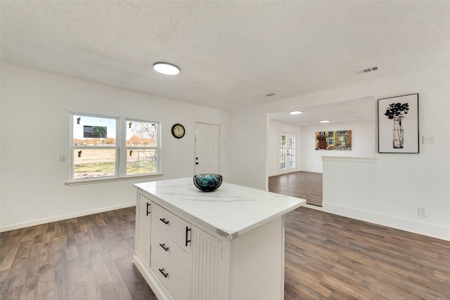 kitchen featuring white cabinetry, dark wood-type flooring, a center island, and a textured ceiling