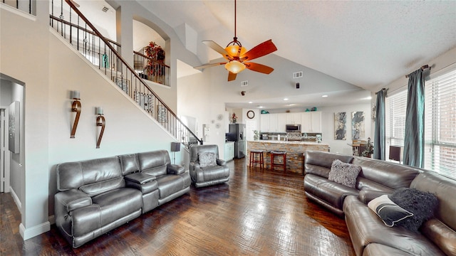 living room with a textured ceiling, ceiling fan, dark wood-type flooring, and high vaulted ceiling