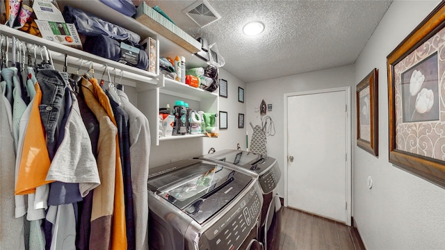 washroom with washing machine and clothes dryer, hardwood / wood-style floors, and a textured ceiling