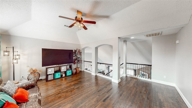 living room with a textured ceiling, lofted ceiling, ceiling fan, and dark hardwood / wood-style floors