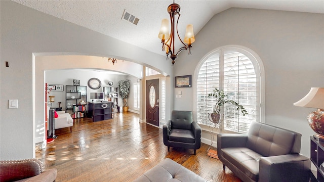 living room with a textured ceiling, hardwood / wood-style flooring, vaulted ceiling, and a notable chandelier