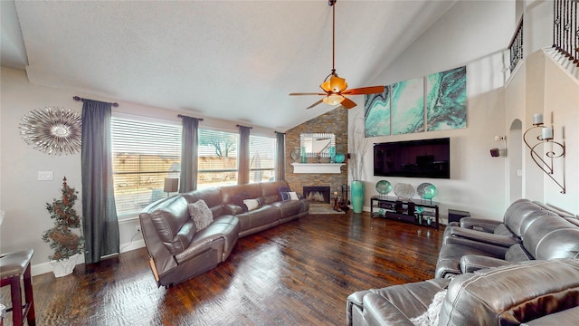 living room with a stone fireplace, ceiling fan, high vaulted ceiling, and dark wood-type flooring