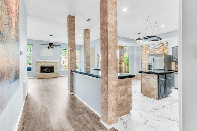 kitchen featuring a center island, stainless steel fridge with ice dispenser, a textured ceiling, and a wealth of natural light