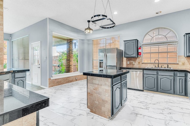 kitchen with decorative backsplash, sink, pendant lighting, and appliances with stainless steel finishes