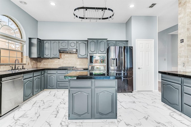 kitchen featuring gray cabinetry, sink, tasteful backsplash, a kitchen island, and appliances with stainless steel finishes