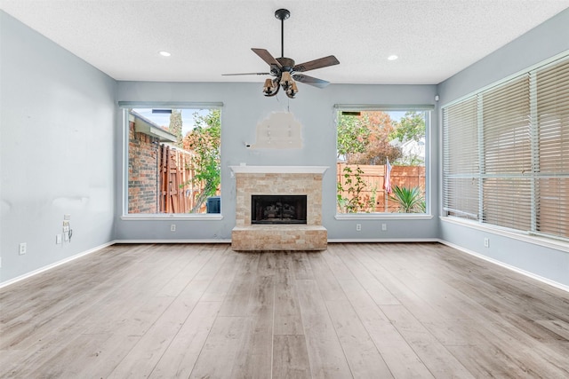 unfurnished living room featuring ceiling fan, light hardwood / wood-style floors, and a textured ceiling