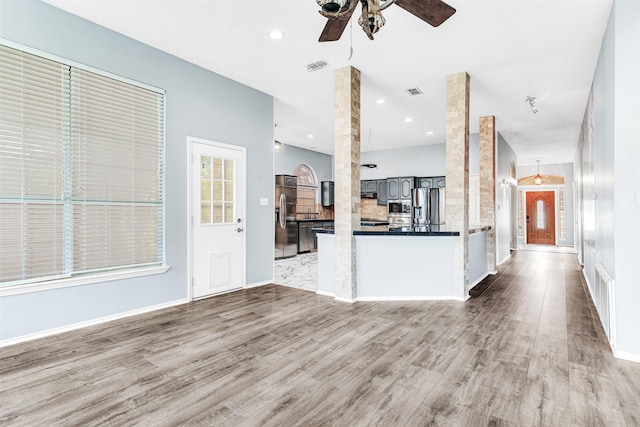 unfurnished living room with ceiling fan, light wood-type flooring, and decorative columns