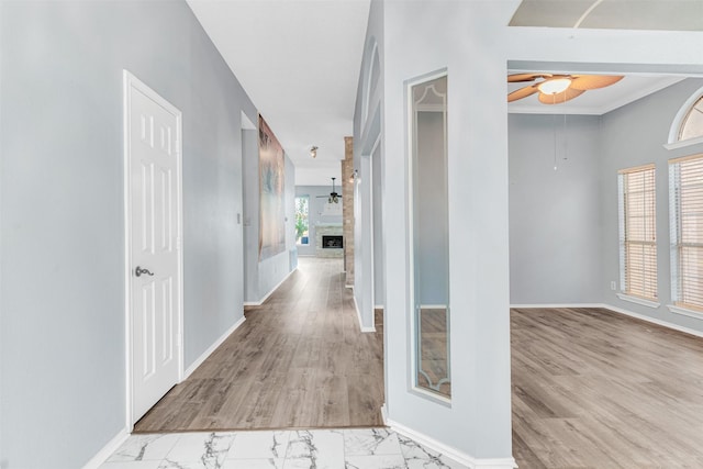 hallway with ornamental molding, a healthy amount of sunlight, and light hardwood / wood-style floors