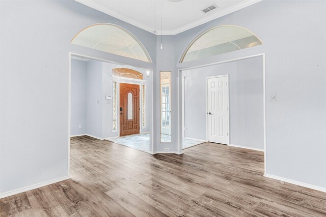 foyer entrance with hardwood / wood-style floors, ornamental molding, and a high ceiling