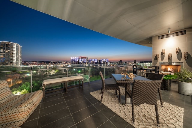 balcony at dusk featuring a patio and exterior fireplace