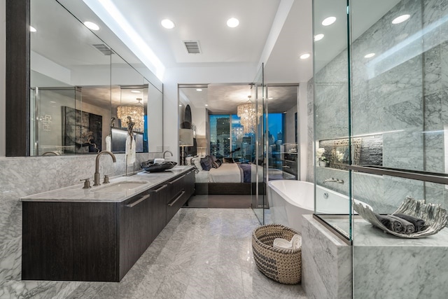 bathroom with a relaxing tiled tub, vanity, and an inviting chandelier