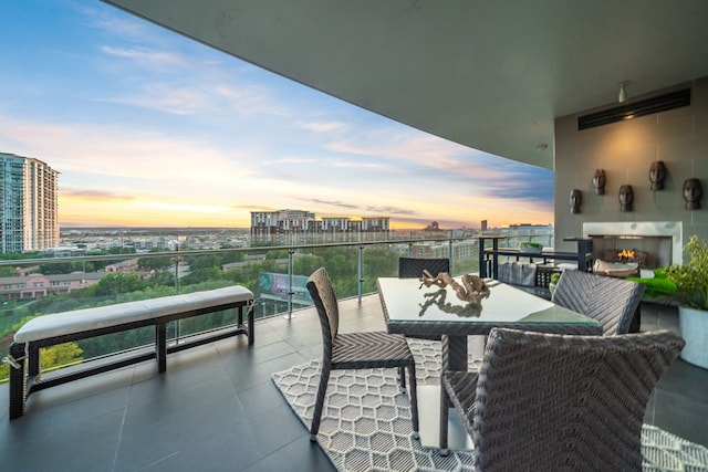 balcony at dusk featuring exterior fireplace