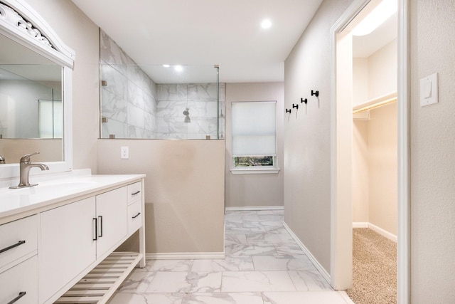 bathroom with a tile shower and vanity