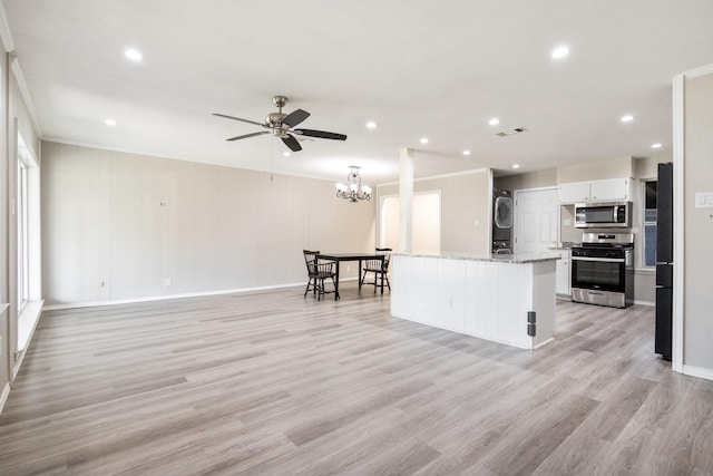 kitchen with stacked washer and dryer, appliances with stainless steel finishes, a center island, light stone counters, and white cabinets