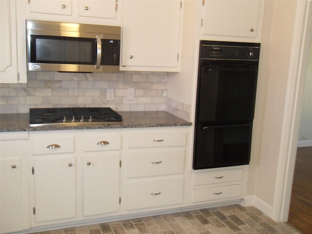 kitchen with backsplash, stainless steel appliances, dark stone counters, and white cabinets