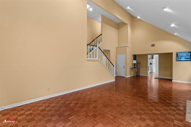 unfurnished living room with parquet floors and high vaulted ceiling