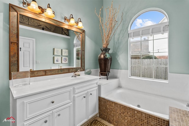 bathroom featuring a relaxing tiled tub and vanity