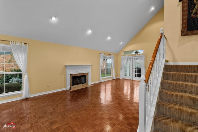 unfurnished living room featuring a premium fireplace, french doors, parquet floors, and high vaulted ceiling