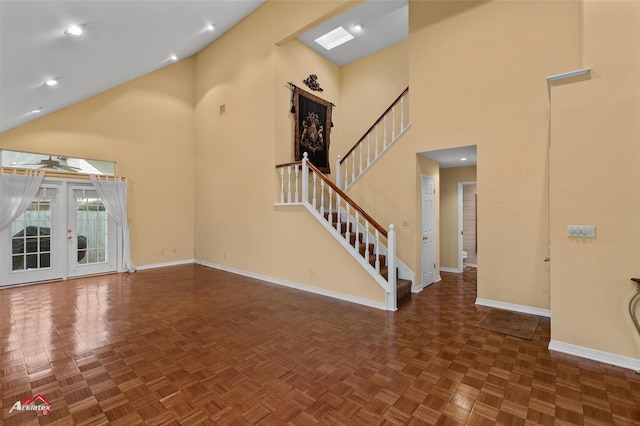 unfurnished living room with a high ceiling, dark parquet floors, and french doors