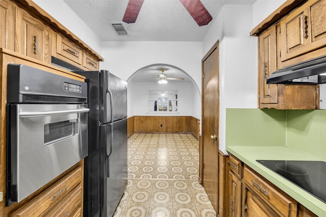 kitchen featuring a textured ceiling, ventilation hood, ceiling fan, and black appliances