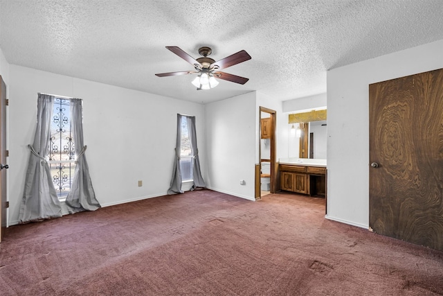 unfurnished bedroom featuring carpet, ensuite bathroom, multiple windows, and ceiling fan