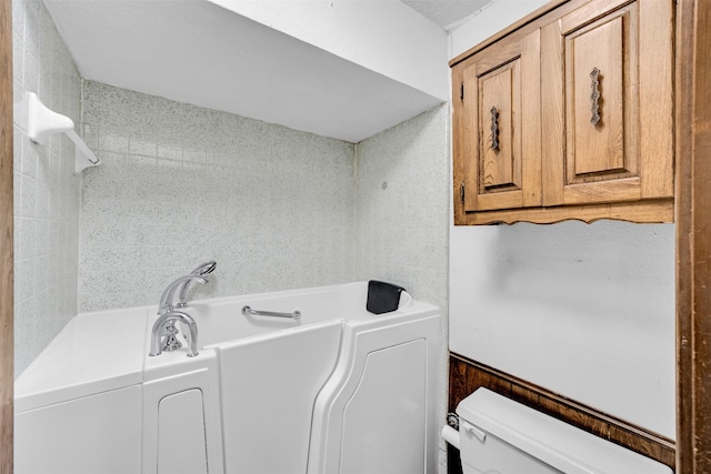 bathroom with a washtub and toilet