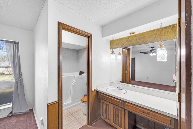 bathroom with ceiling fan, toilet, a textured ceiling, and vanity