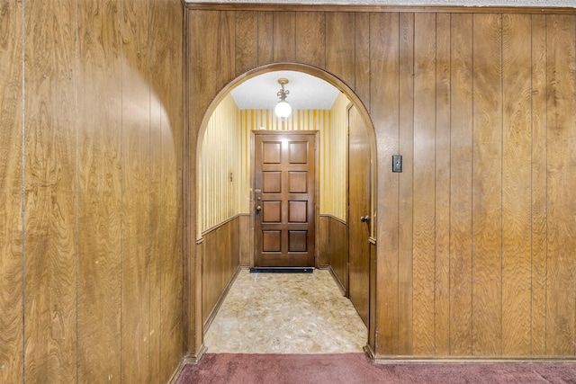 doorway to outside with carpet and wood walls