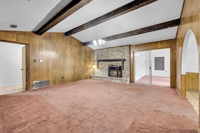 unfurnished living room featuring wood walls, carpet floors, and a brick fireplace