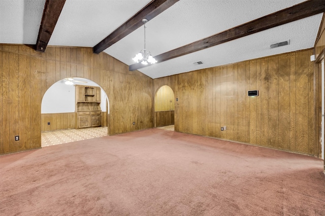 unfurnished living room with carpet floors, lofted ceiling with beams, wooden walls, and a notable chandelier