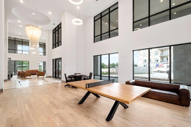 recreation room with a notable chandelier, light hardwood / wood-style flooring, and plenty of natural light