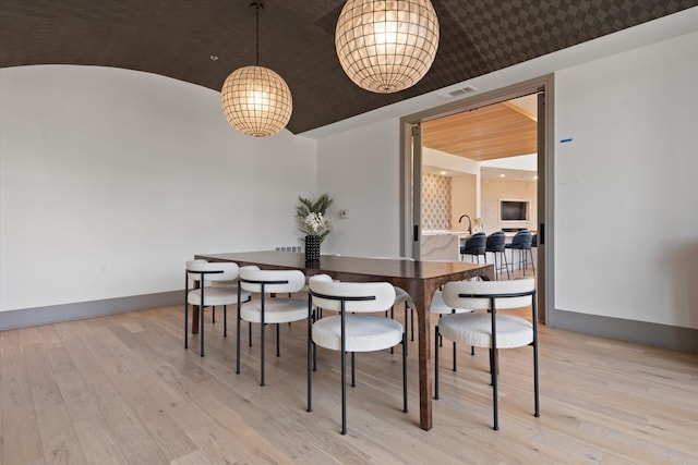 dining area featuring vaulted ceiling and light wood-type flooring