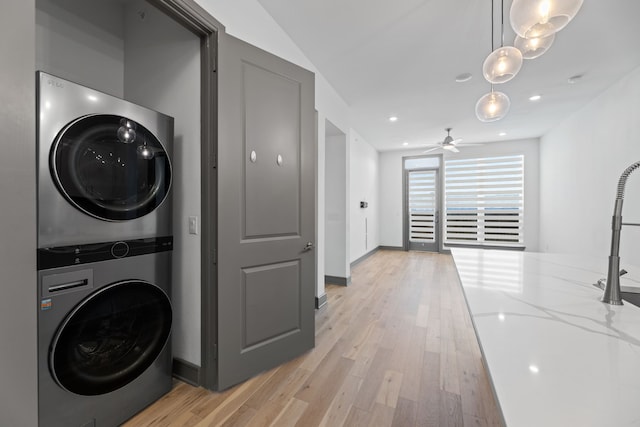 laundry area featuring ceiling fan, light hardwood / wood-style floors, and stacked washer and clothes dryer