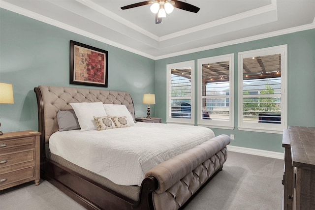 bedroom with light carpet, a tray ceiling, ornamental molding, and ceiling fan