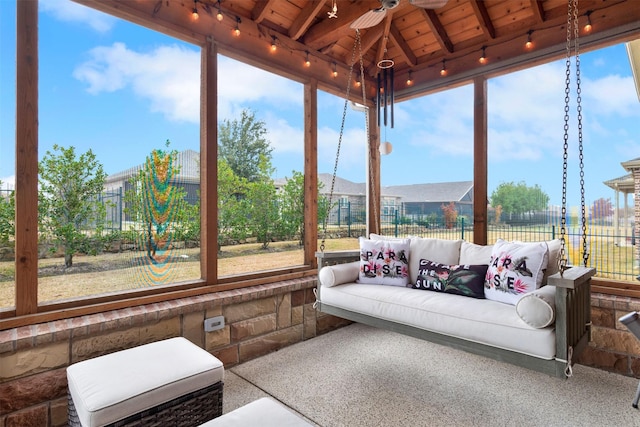 sunroom with ceiling fan, lofted ceiling with beams, a wealth of natural light, and wood ceiling