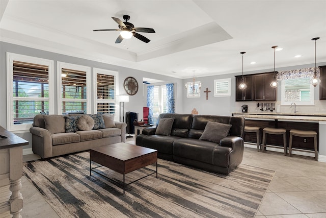 tiled living room with a raised ceiling, ornamental molding, and plenty of natural light